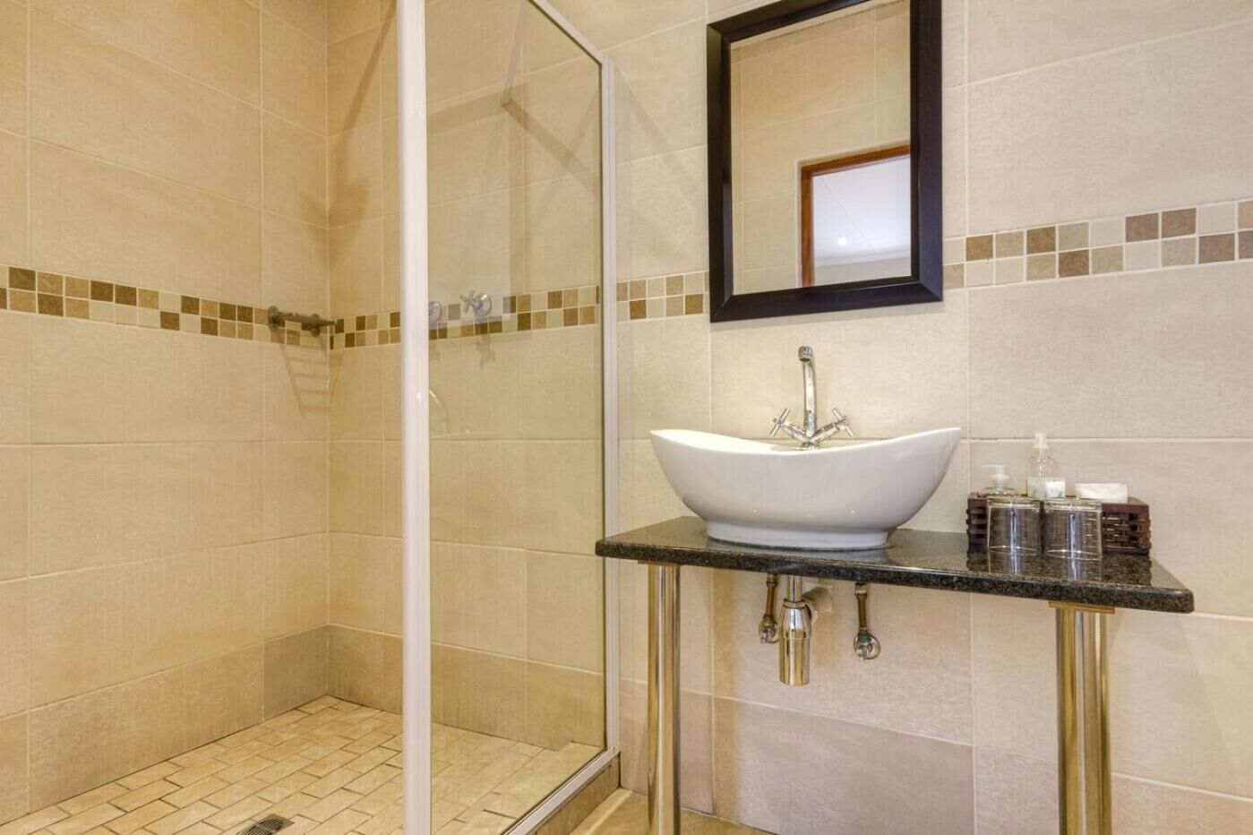 Une salle de bain avec une douche à parois de verre, un lavabo sur colonne blanc et un miroir au-dessus.