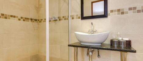 A bathroom with a glass-enclosed shower, a white vessel sink, and a mirror above it.