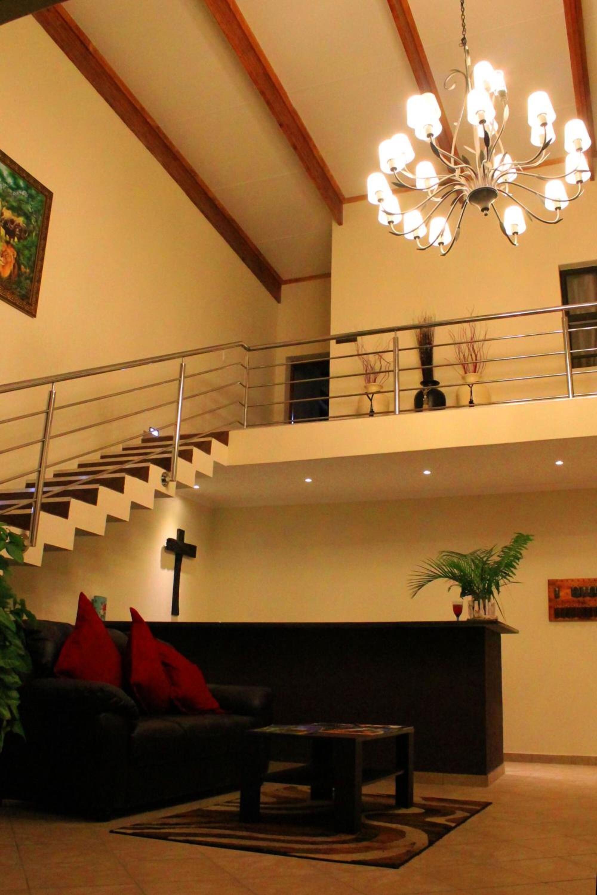 A spacious living area with a staircase, a chandelier, a sofa, and a coffee table.