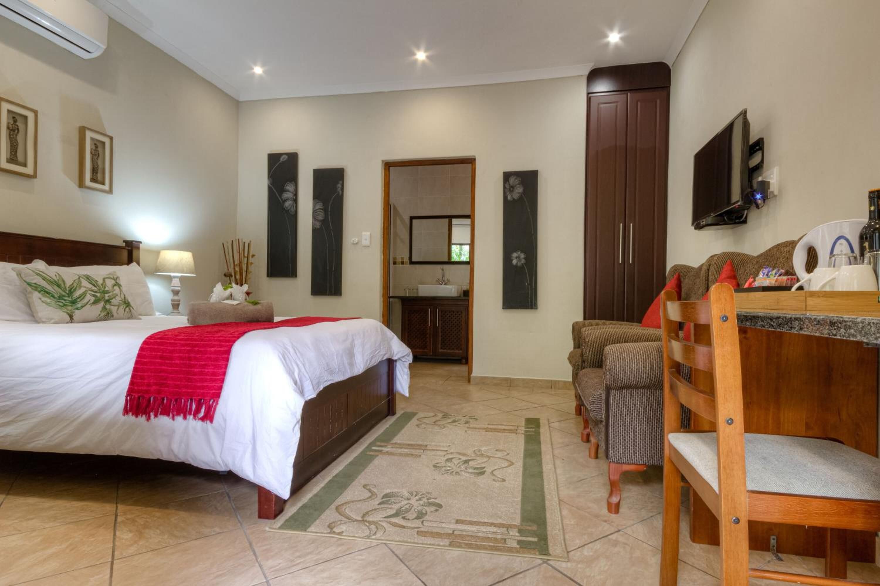 A hotel room with a bed, a desk, a chair, a TV, and a wardrobe.