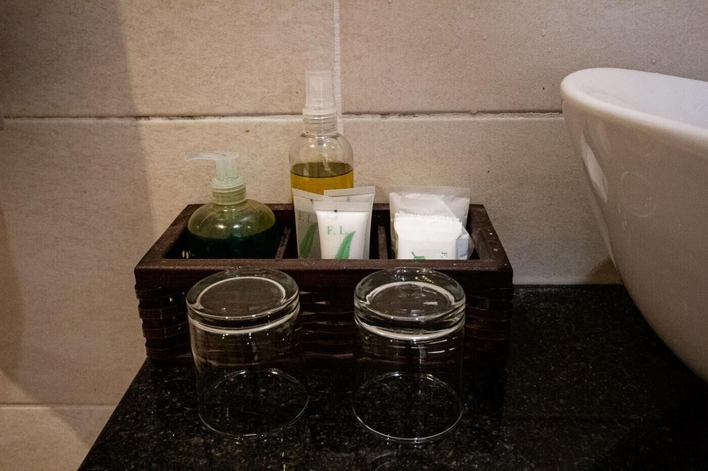 A bathroom counter with a soap dispenser, lotion, and a toothbrush holder.