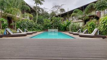 A pool area with lounge chairs and tropical vegetation.