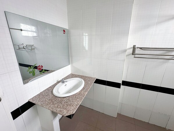 Un baño con un lavamanos blanco, un espejo y un perchero para toallas.