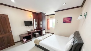 Habitación de hotel con cama, escritorio, computadora, televisor y armario.