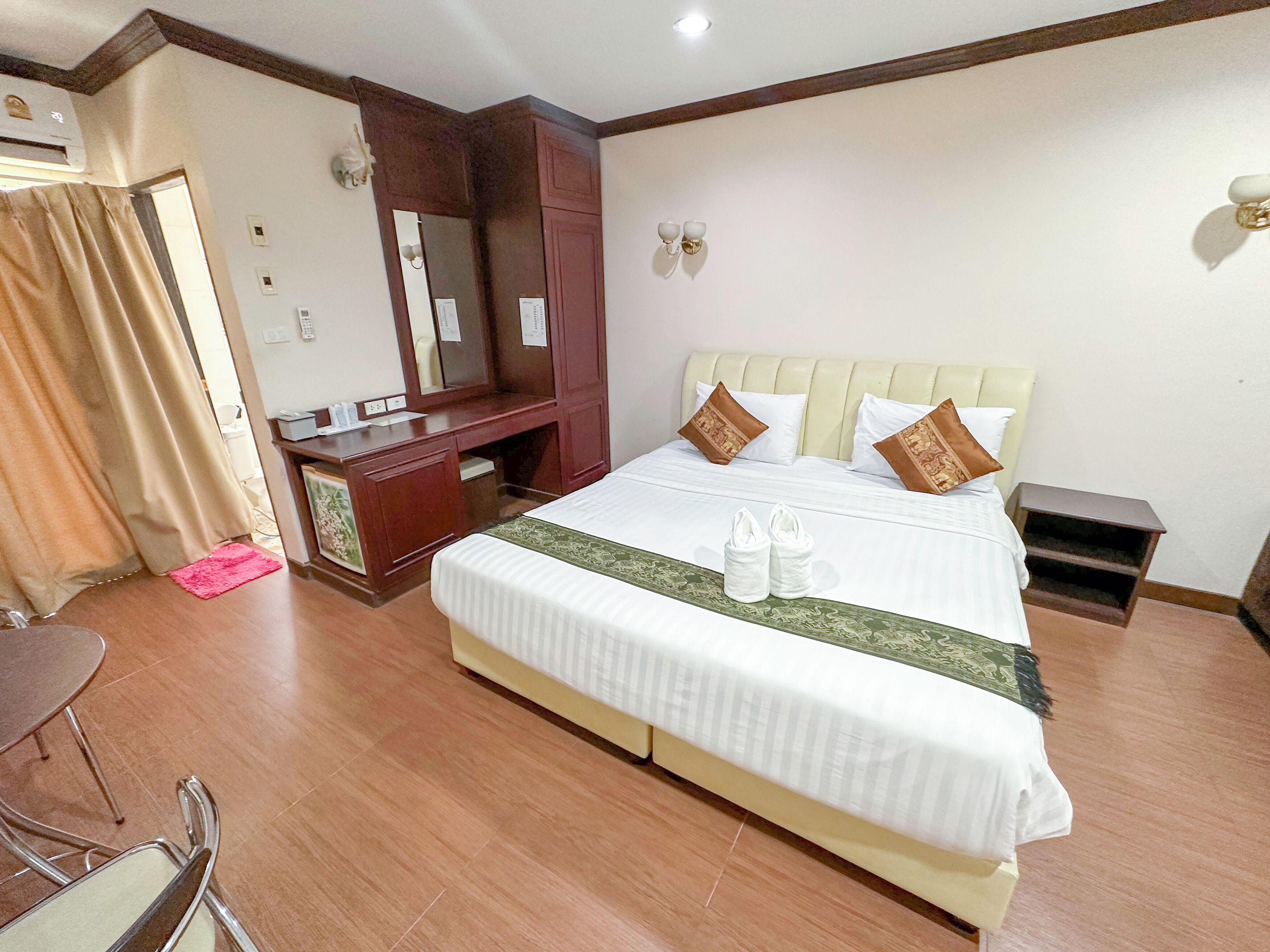 A hotel room with a bed, a desk, a chair, and a mirror.
