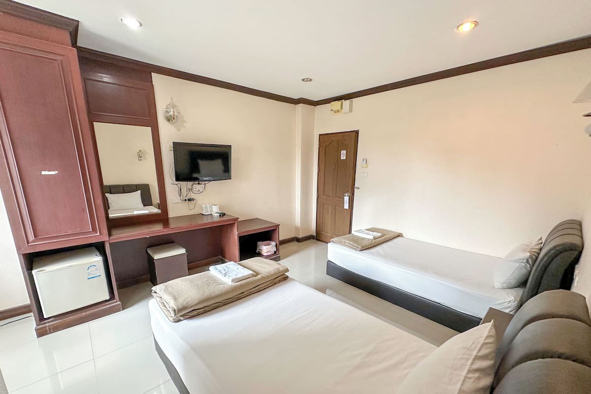 Een hotelkamer met een groot bed, een bureau met een flatscreen televisie, een kledingkast en een kleine koelkast.