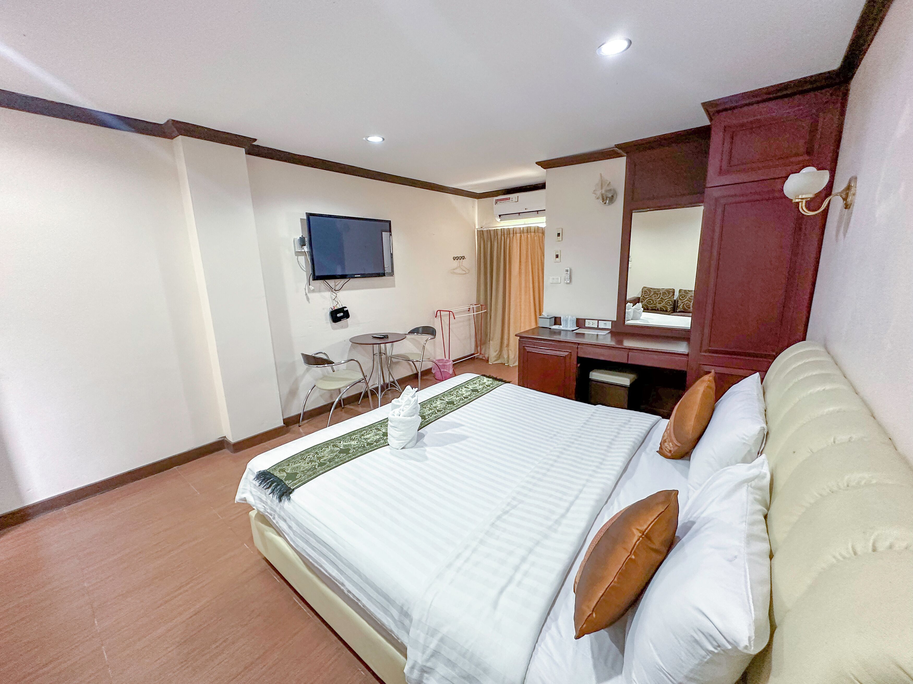 A hotel room with a bed, a desk, a chair, a television, and a mirror.