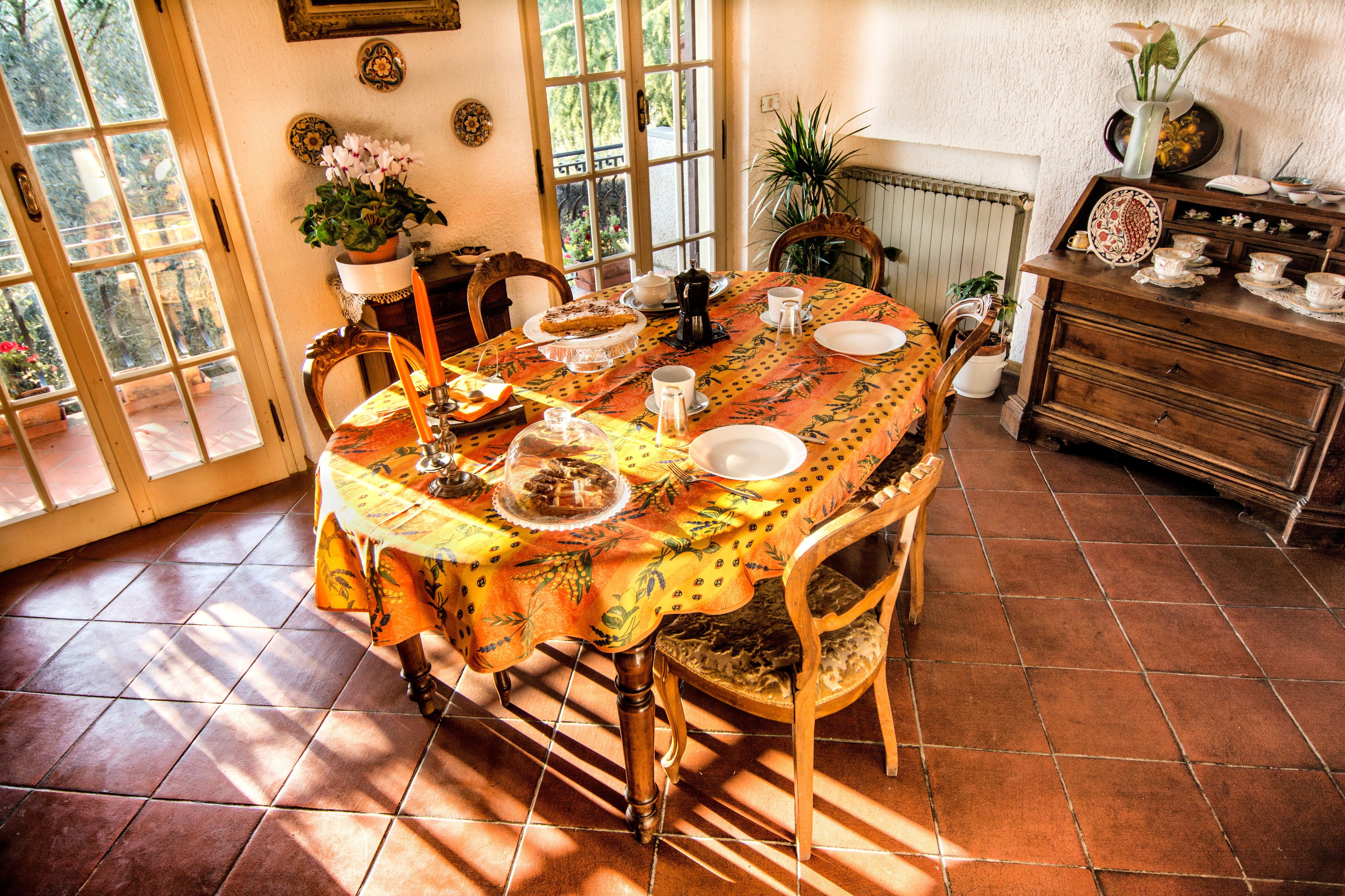 A dining area with a table set for four, surrounded by chairs, a radiator, and a wooden cabinet with dishes.