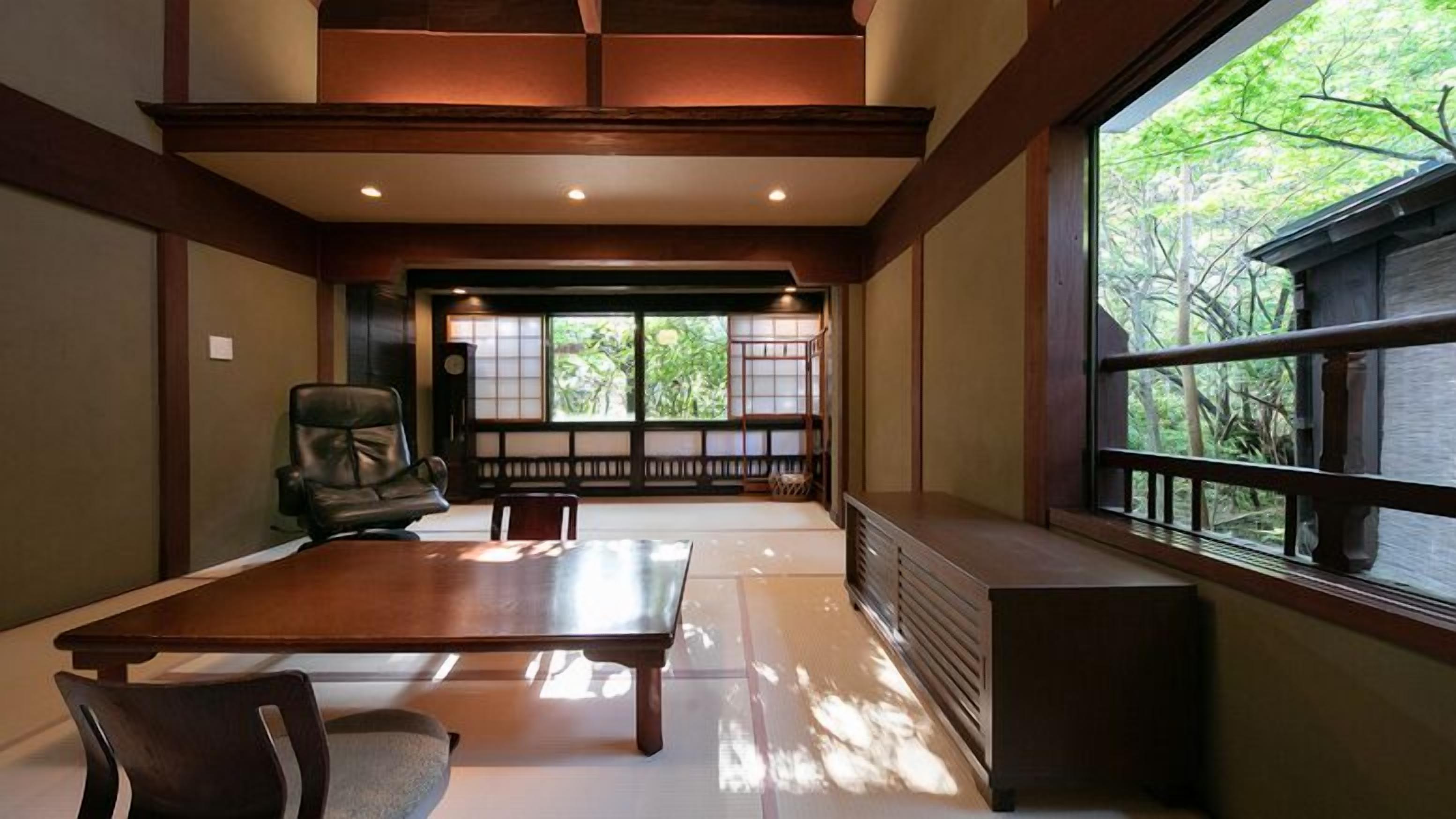 A traditional Japanese-style room with tatami flooring, a low table, and a view of greenery outside.
