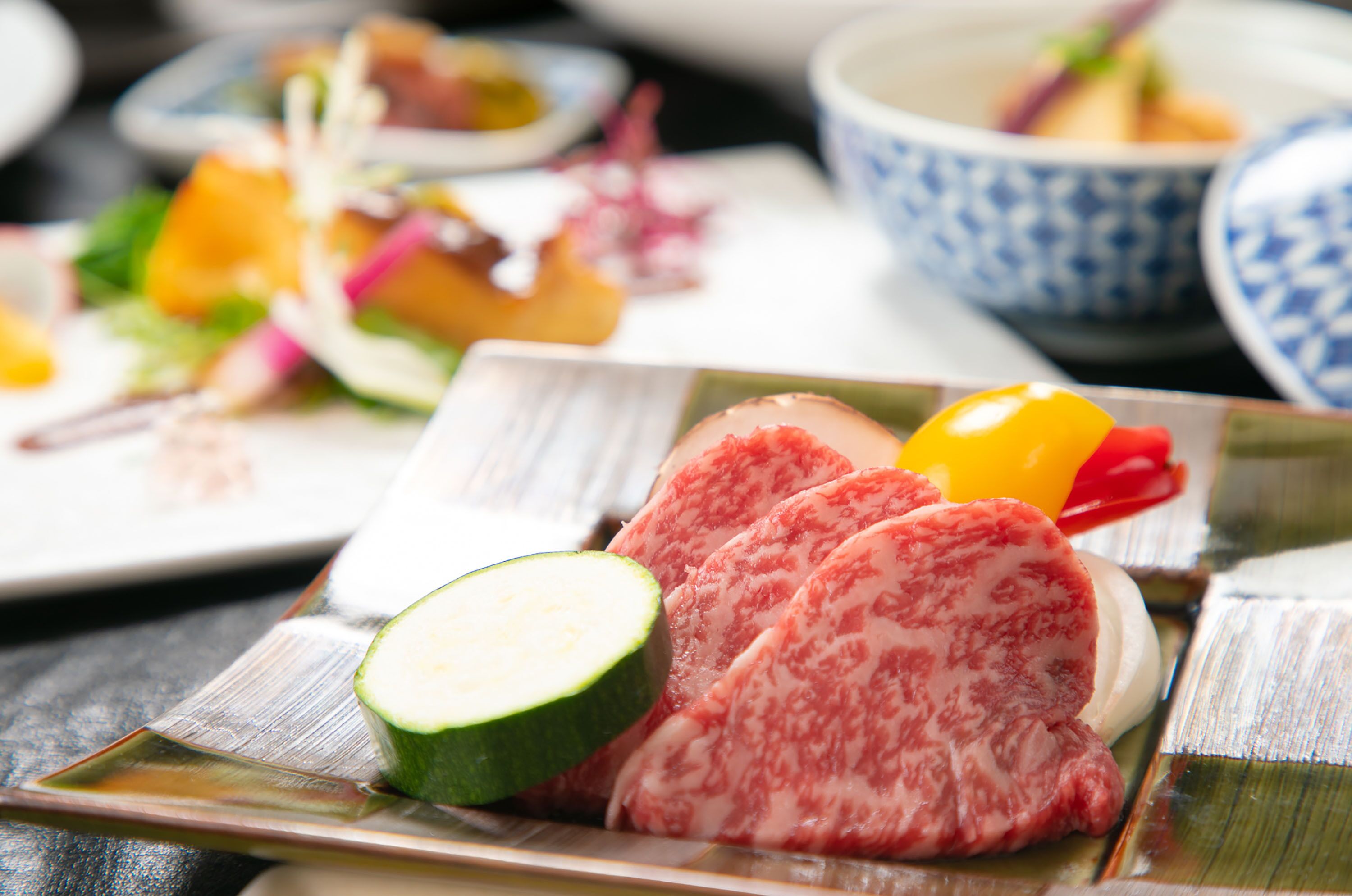 A plate with sliced meat, a cucumber, and a bell pepper.