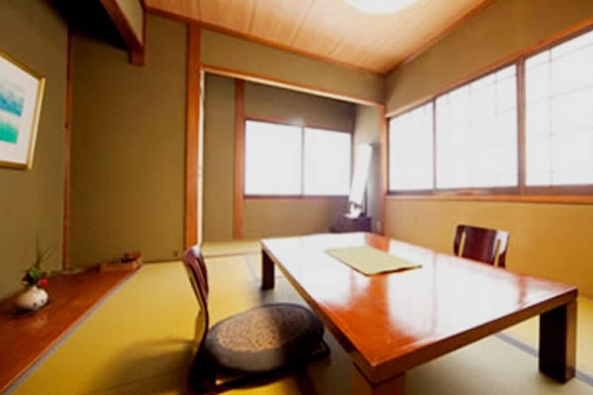 Una habitación de estilo japonés tradicional con suelo de tatami, una mesa de madera baja y puertas correderas.