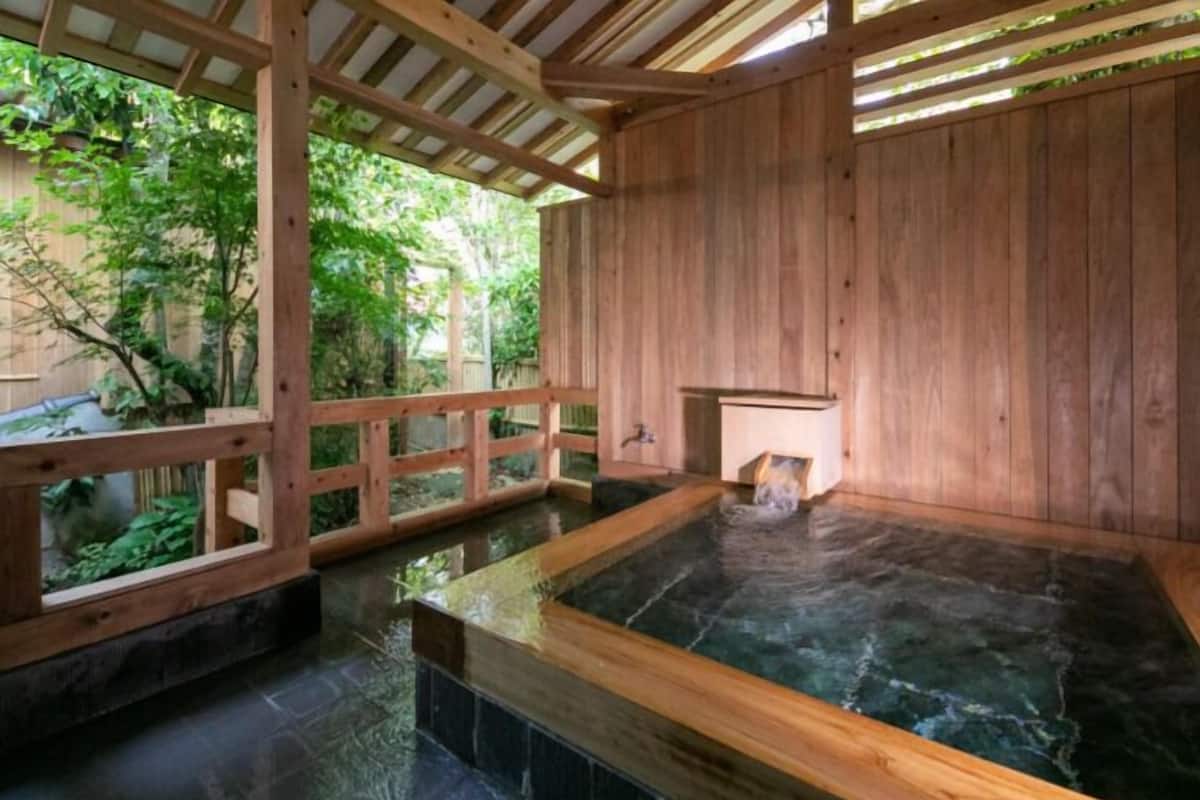 Un spa de madera con jacuzzi, paredes de madera y vistas a la vegetación exterior.