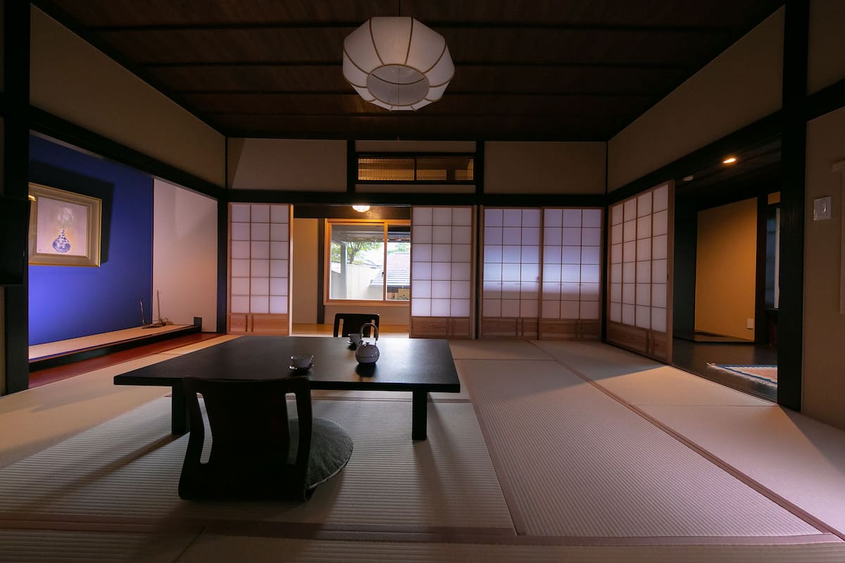 Una habitación japonesa tradicional con suelo de tatami, una mesa baja y puertas correderas.