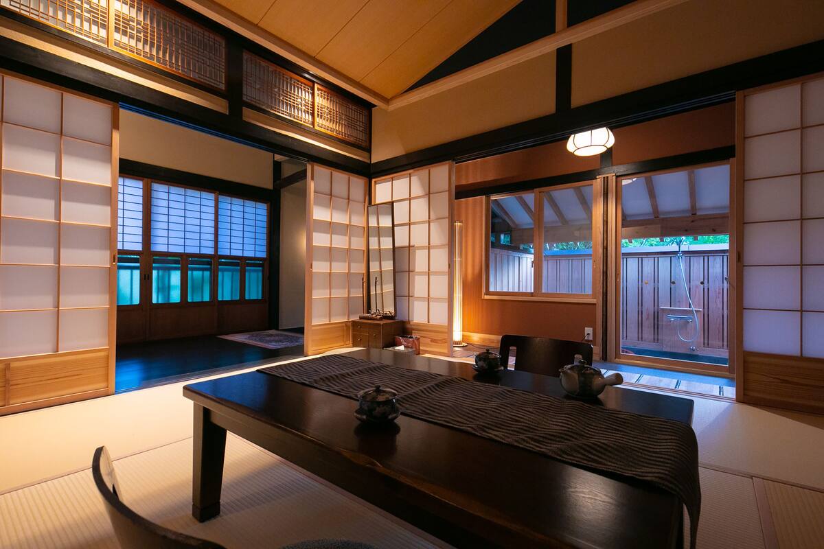 Una habitación japonesa tradicional con suelo de tatami, puertas correderas y una mesa baja con un juego de té.