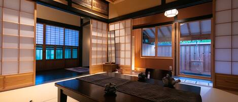 A traditional Japanese room with tatami flooring, sliding doors, and a low table with a tea set.