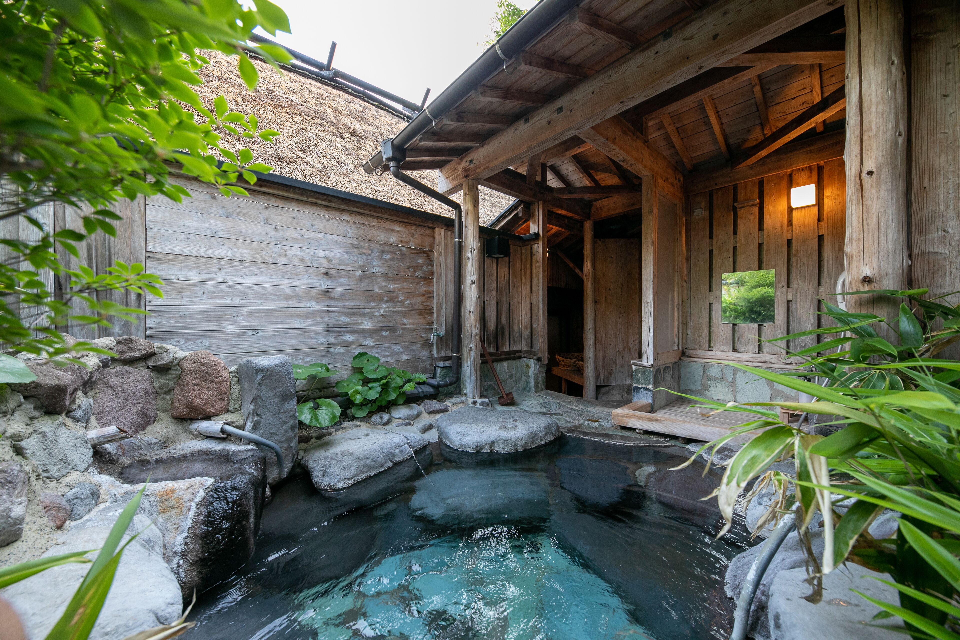 Una cabaña de madera con un pequeño estanque y una terraza de madera.