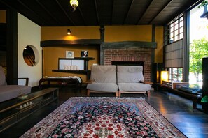 Un salón acogedor con un tapete grande con estampado floral, una chimenea de ladrillo y un sofá.