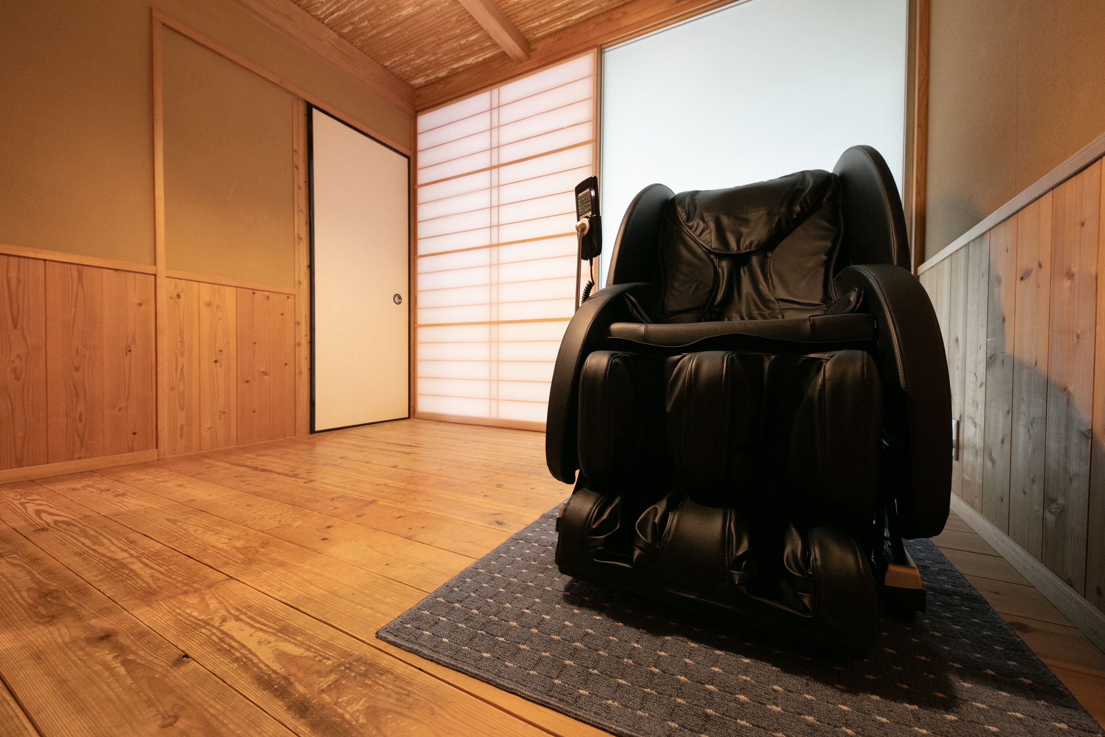 Una silla de masaje en una habitación con suelo de madera y puerta corredera.