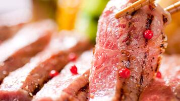 A close-up of sliced meat with chopsticks, garnished with red berries.