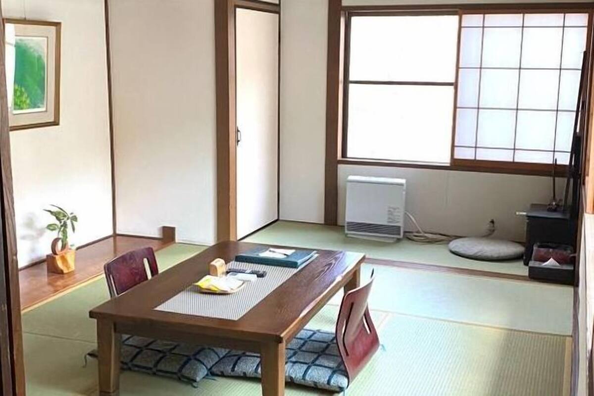 Una habitación tradicional japonesa con suelo de tatami, una mesa baja con cojines y una puerta corredera.