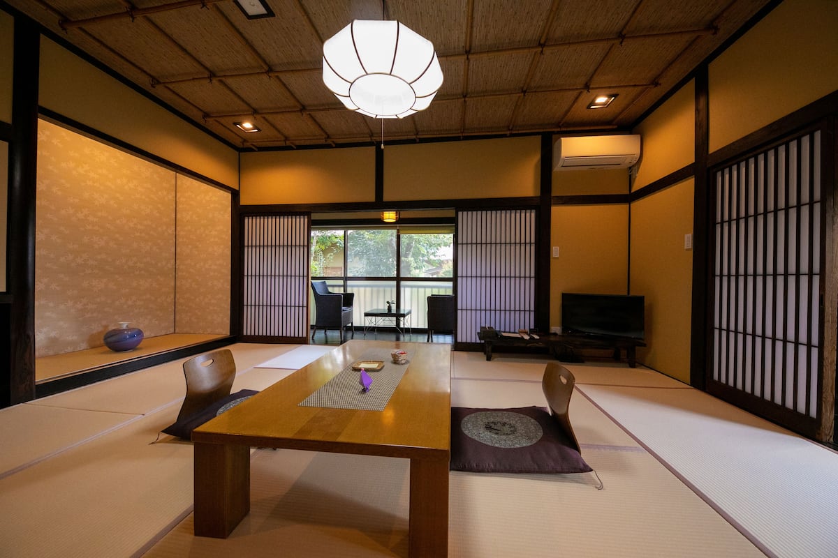 Una habitación japonesa tradicional con suelo de tatami, una baja mesa de madera y puertas correderas shoji.