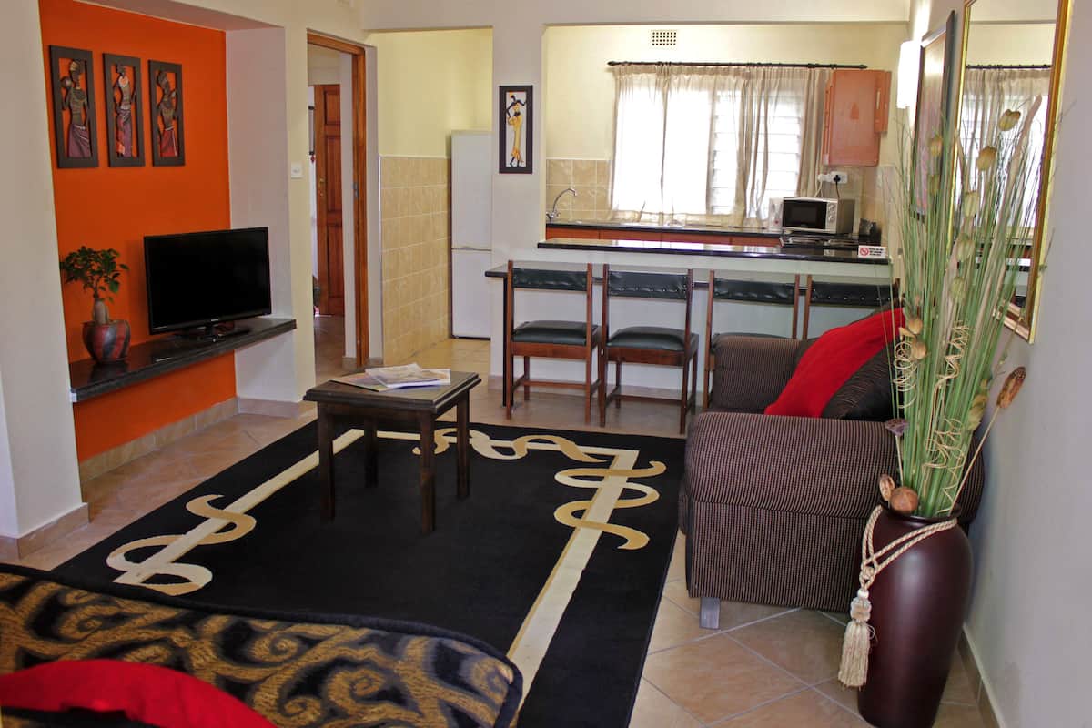 A living room with a TV, sofa, and a dining area with chairs and a table.
