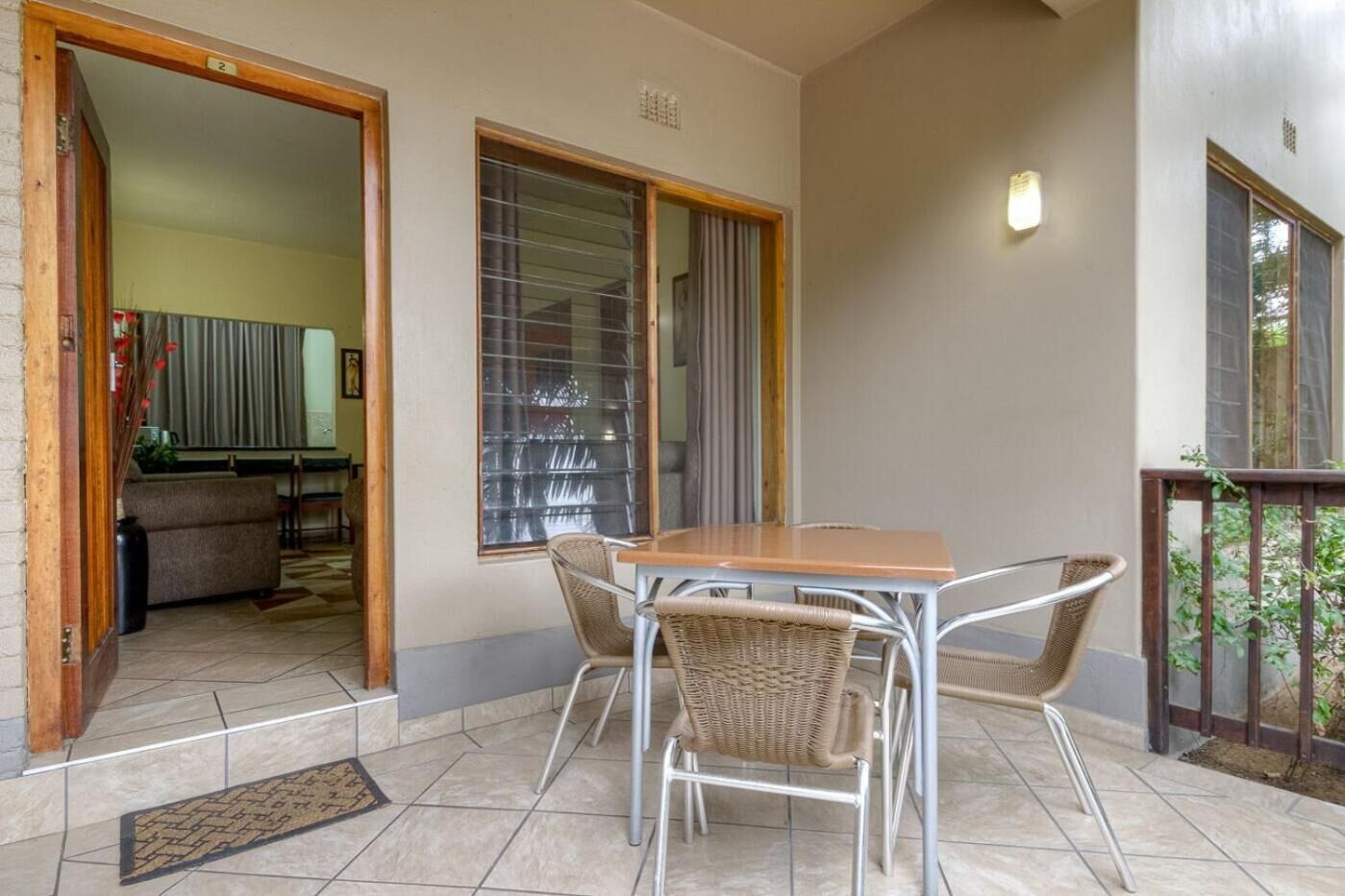A balcony with a table and chairs, a view of the outside, and a door leading to an interior space.