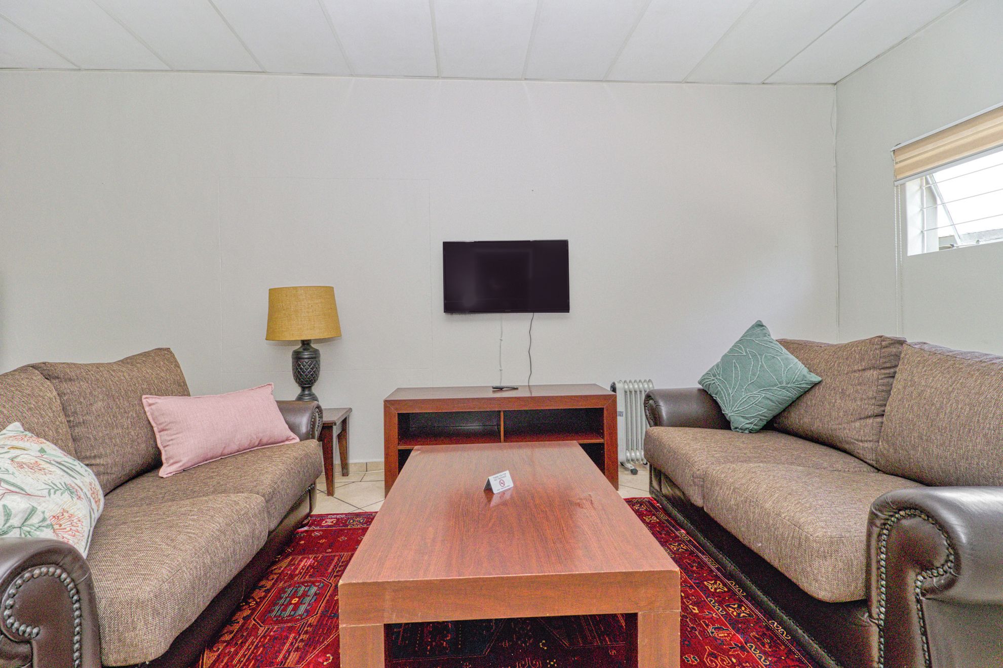 Sala de estar com dois sofás, uma mesa de centro, uma televisão e um abajur.