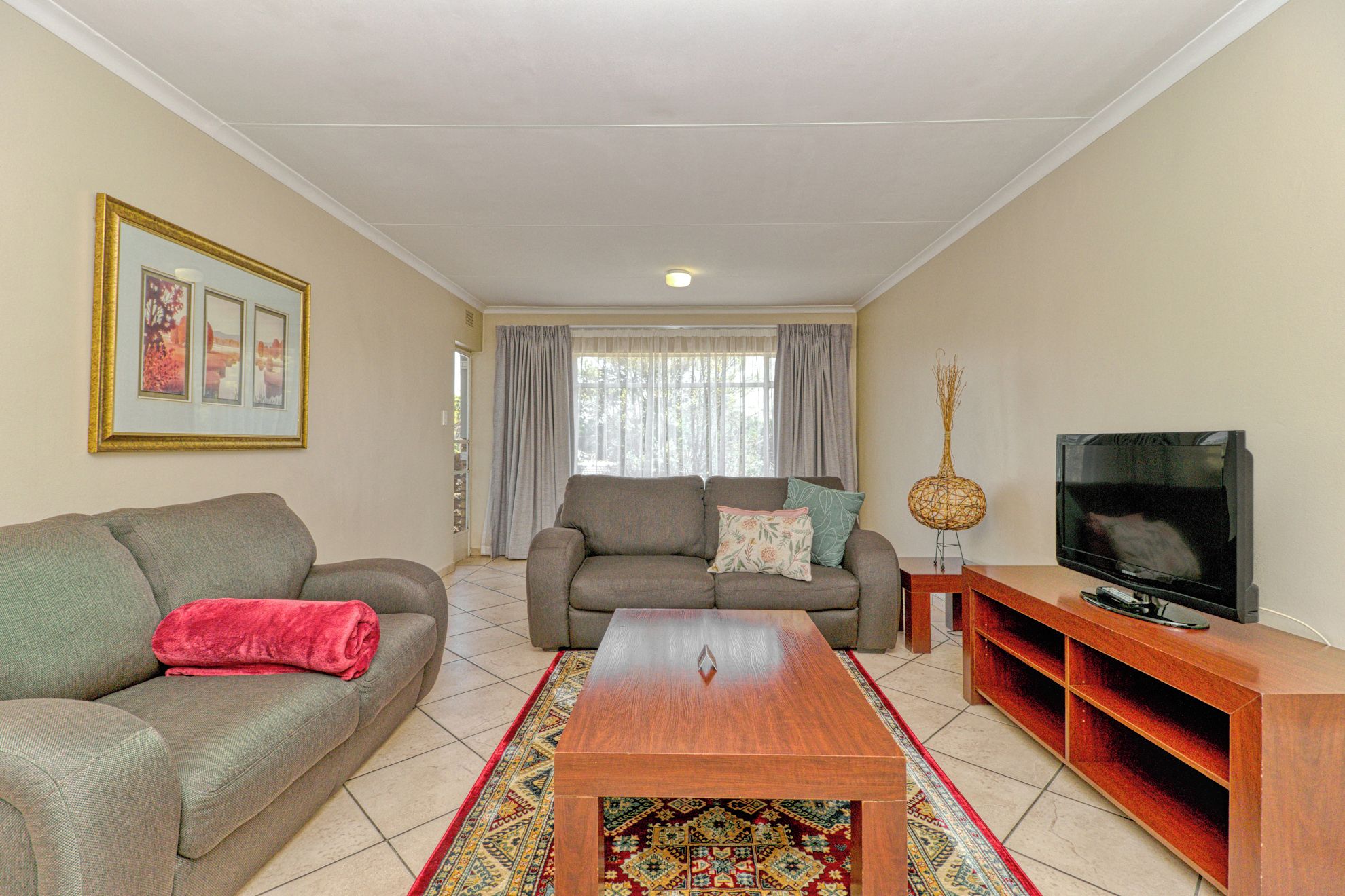 A living room with a sofa, a coffee table, a TV, and a decorative vase.