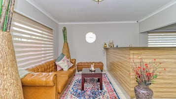 Ein Wohnzimmer mit einem braunen Ledersofa, einem Holztisch und einem gemusterten Teppich.