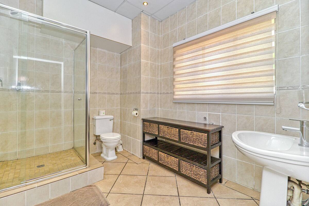 A bathroom with a glass shower enclosure, a toilet, a vanity with wicker baskets, and a sink.