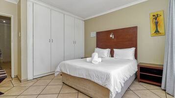 A hotel room with a bed, a wardrobe, a painting on the wall, and a staircase leading to another room.