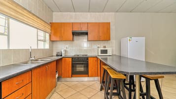 Eine moderne Küche mit Holzausstattung, einer schwarzen Arbeitsplatte, einem eingebauten Ofen, einer Mikrowelle und einem Kühlschrank.