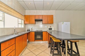 Une cuisine moderne avec des meubles en bois, un plan de travail noir, un four encastré, un four à micro-ondes et un réfrigérateur.