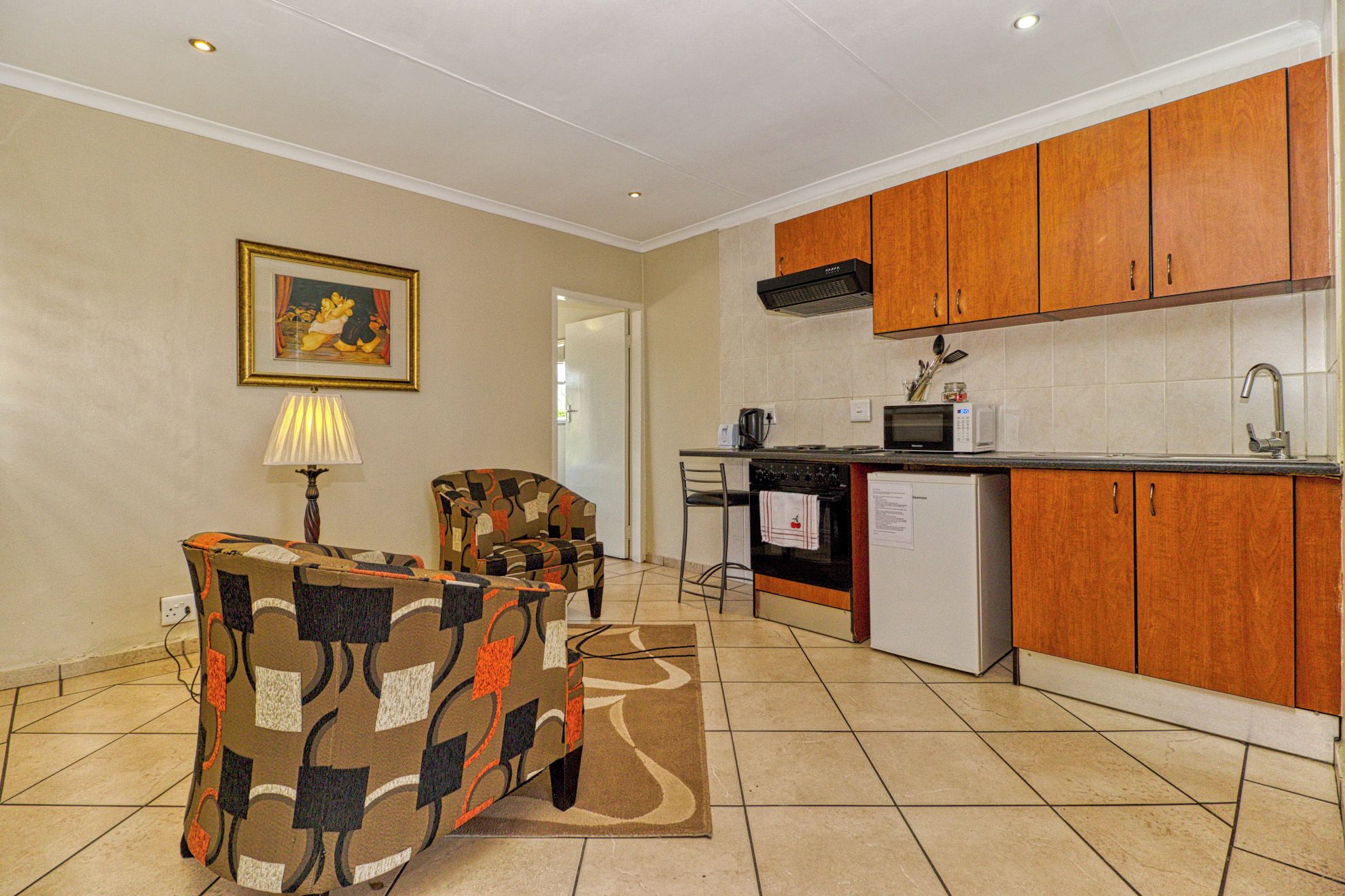 A compact kitchen with wooden cabinets, a microwave, and a refrigerator.