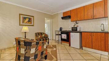 A compact kitchen with wooden cabinets, a microwave, and a refrigerator.
