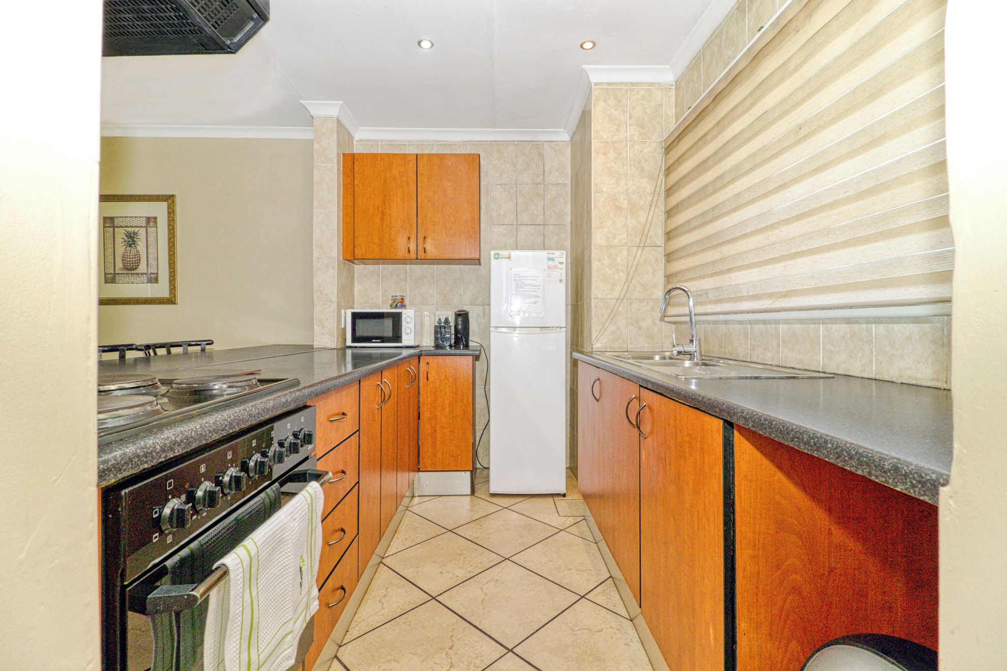 A kitchen with wooden cabinets, a microwave, a refrigerator, and a stove.