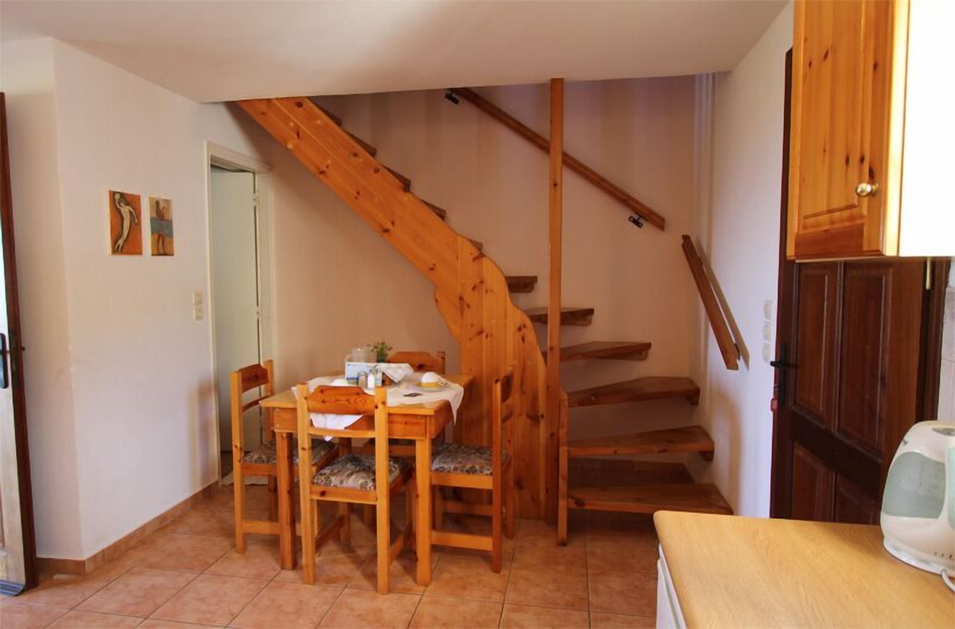 A dining area with a wooden table and chairs, a staircase, and a cabinet.