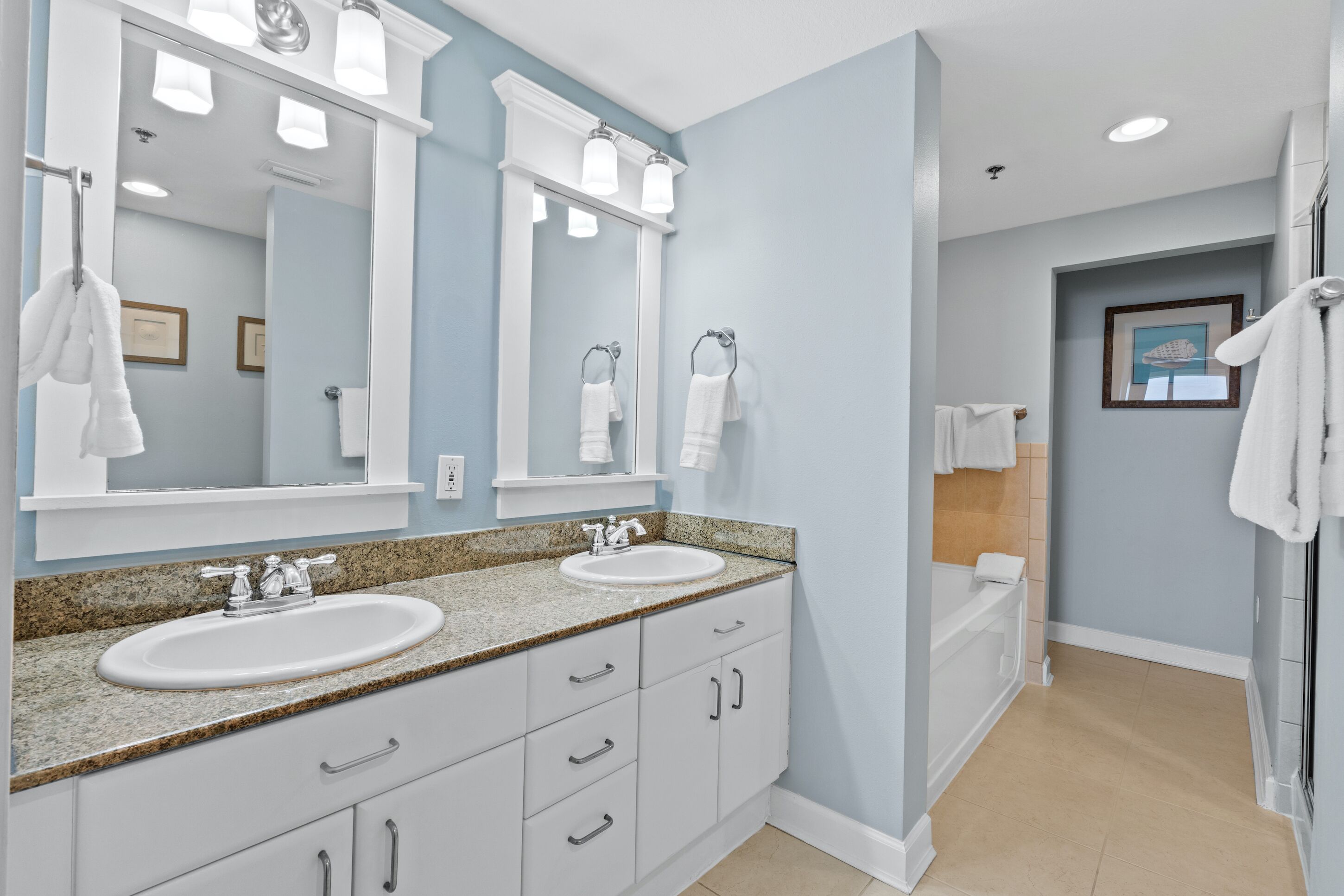 A bathroom with two sinks, a large mirror, and a bathtub.