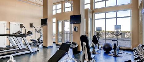 Une salle de sport équipée de tapis de course, d’appareils de musculation et de ballons d’exercice.