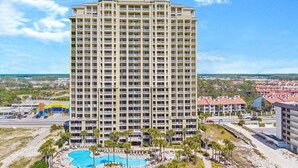 A tall hotel with multiple balconies, a swimming pool, and a beach area. - Grand Panama Beach Resort by Panhandle Getaways (Panama City Beach)