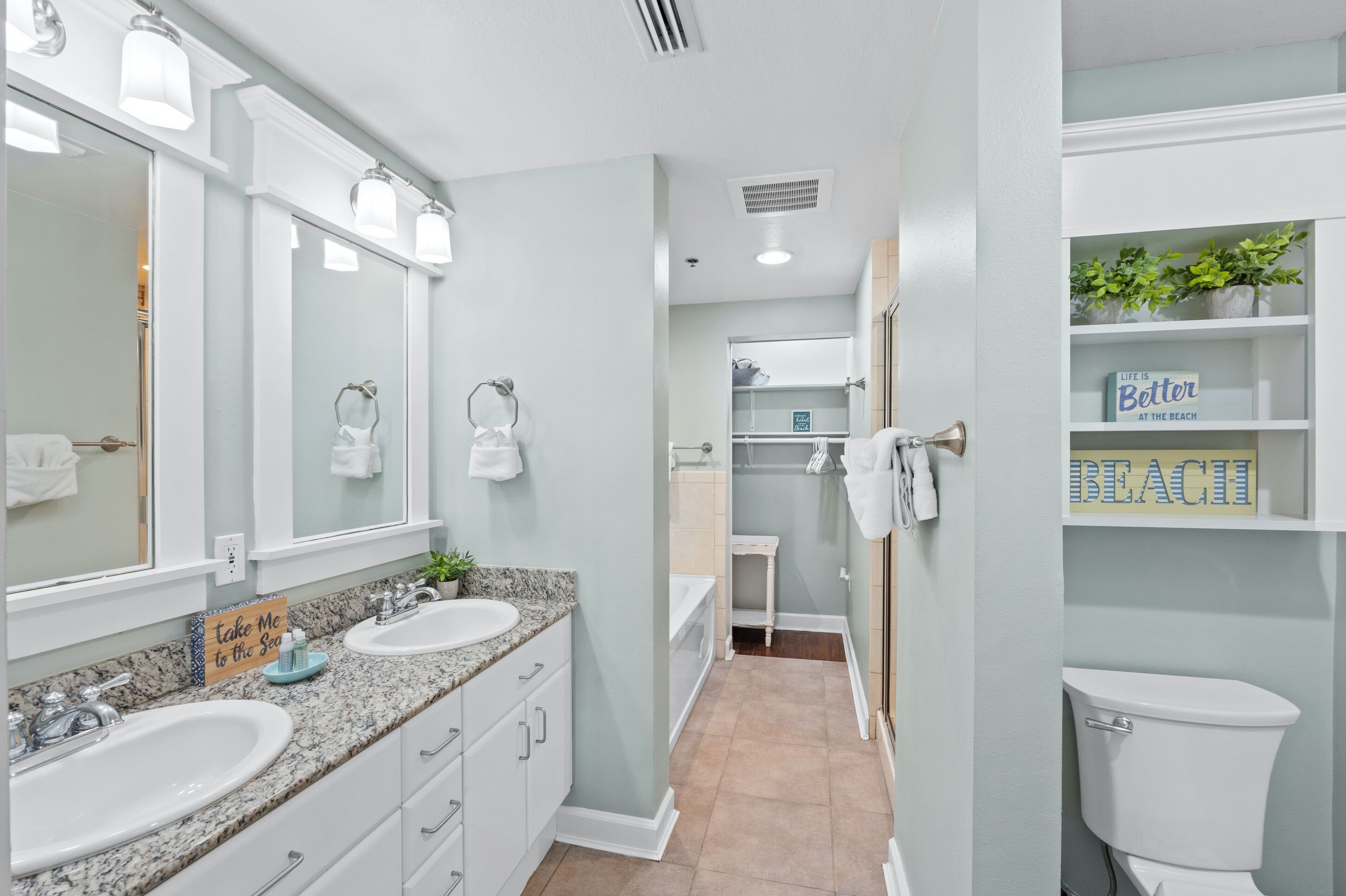 A modern bathroom with two sinks, a large mirror, and a vanity with drawers.