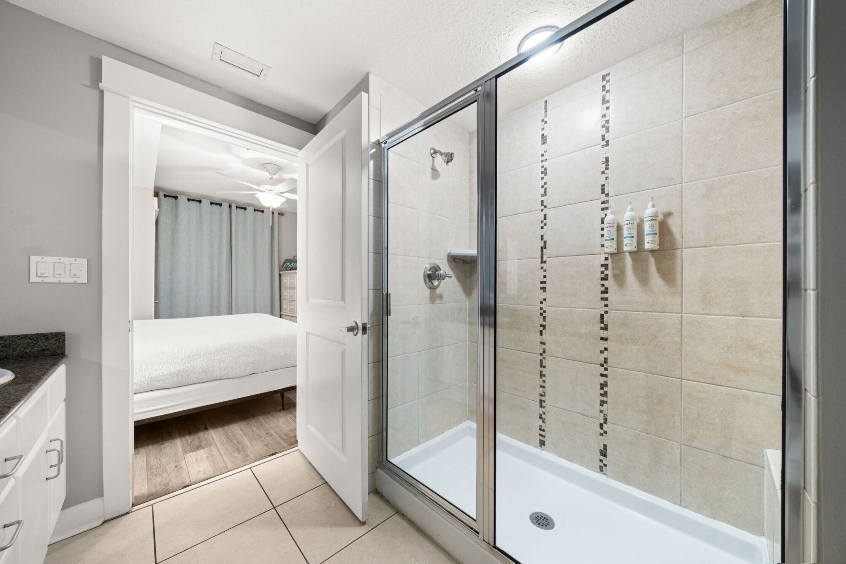 A modern bathroom with a glass-enclosed shower, a white bathtub, and a separate shower area with tiled walls.