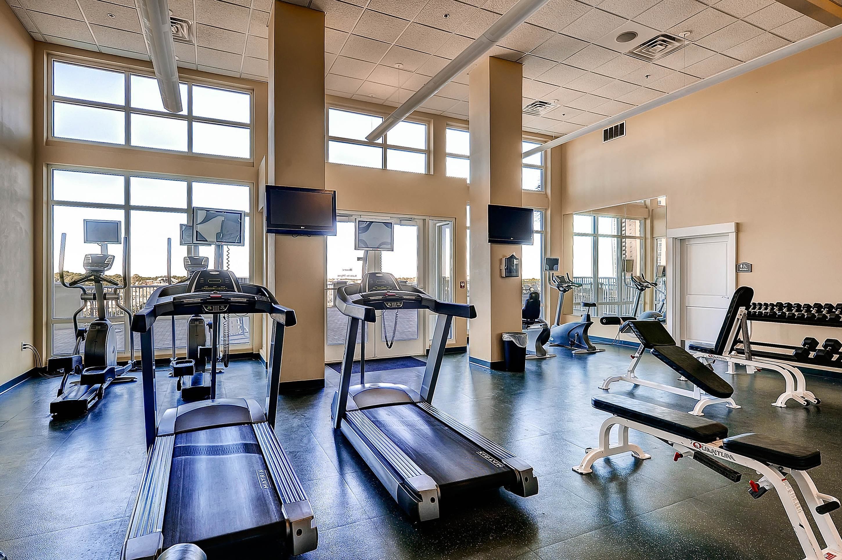 Ein Fitnessstudio mit Laufbändern, Crosstrainern und Gewichteinrichtungen.