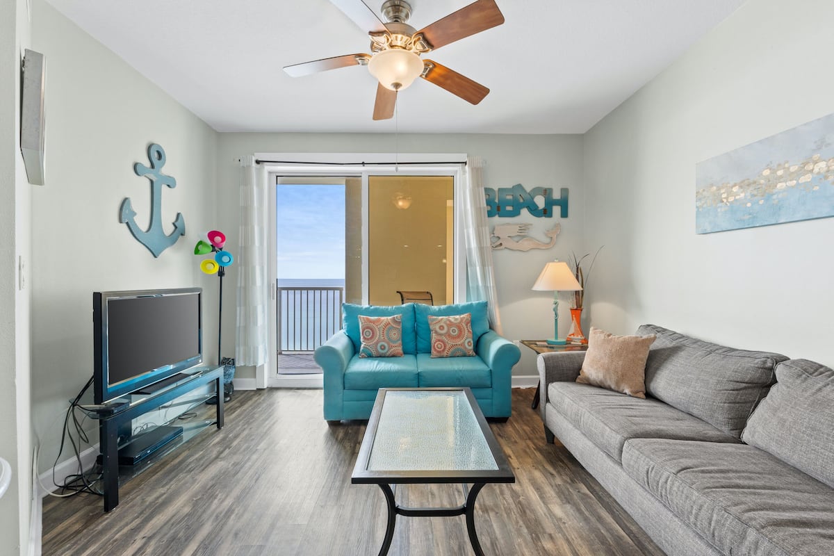 A living room with a TV, two sofas, a coffee table, and a ceiling fan.
