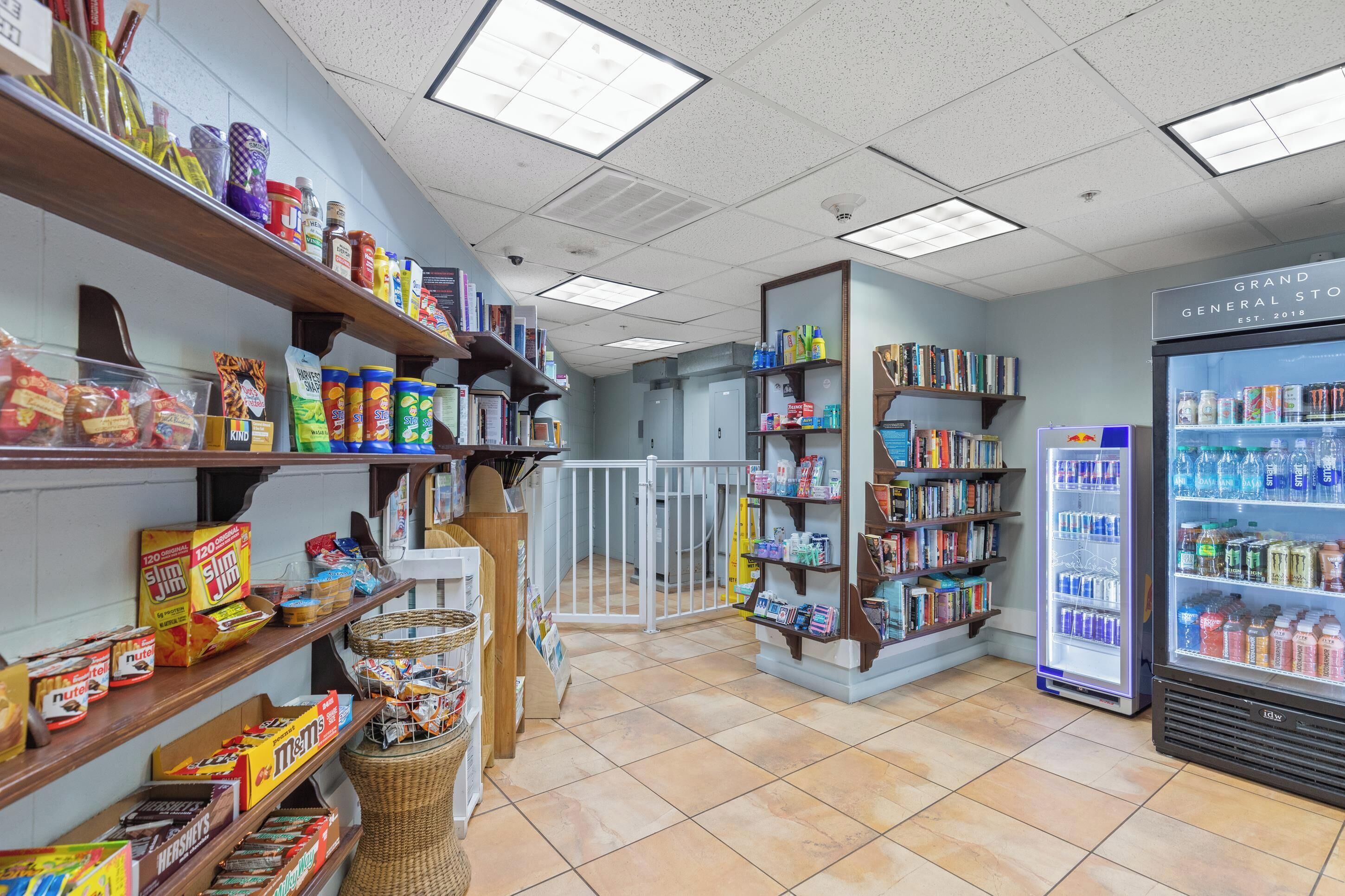 A grocery store interior with shelves stocked with snacks, beverages, and household items.
