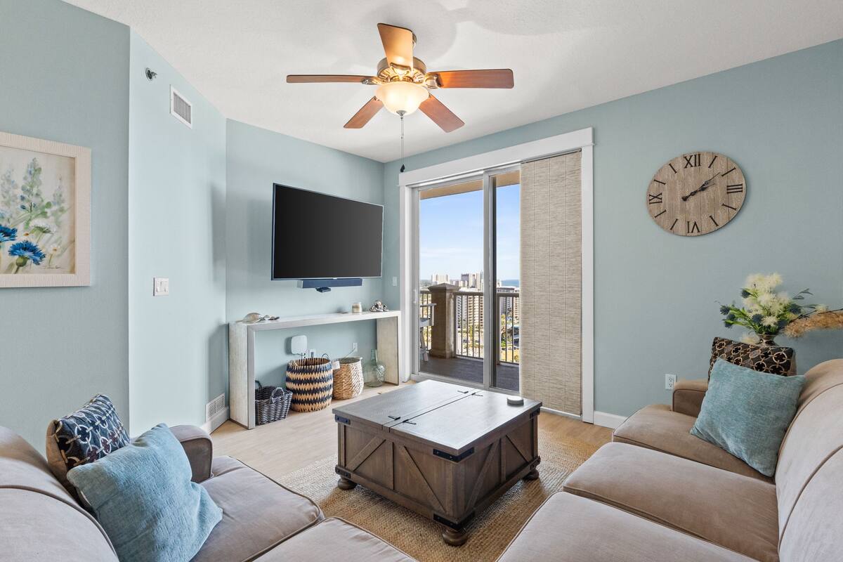A living room with a ceiling fan, a flat-screen TV, a coffee table, and a sofa.