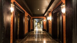 A long, narrow hallway with dark wooden doors and walls, and marble flooring. - Unit Number 318 Cape Royale Luxury Apartments (Cape Town)