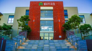 En bygning med en rød murstensfacade, navnet 'MAYFAIR' over indgangen, og en trappe op til døren.