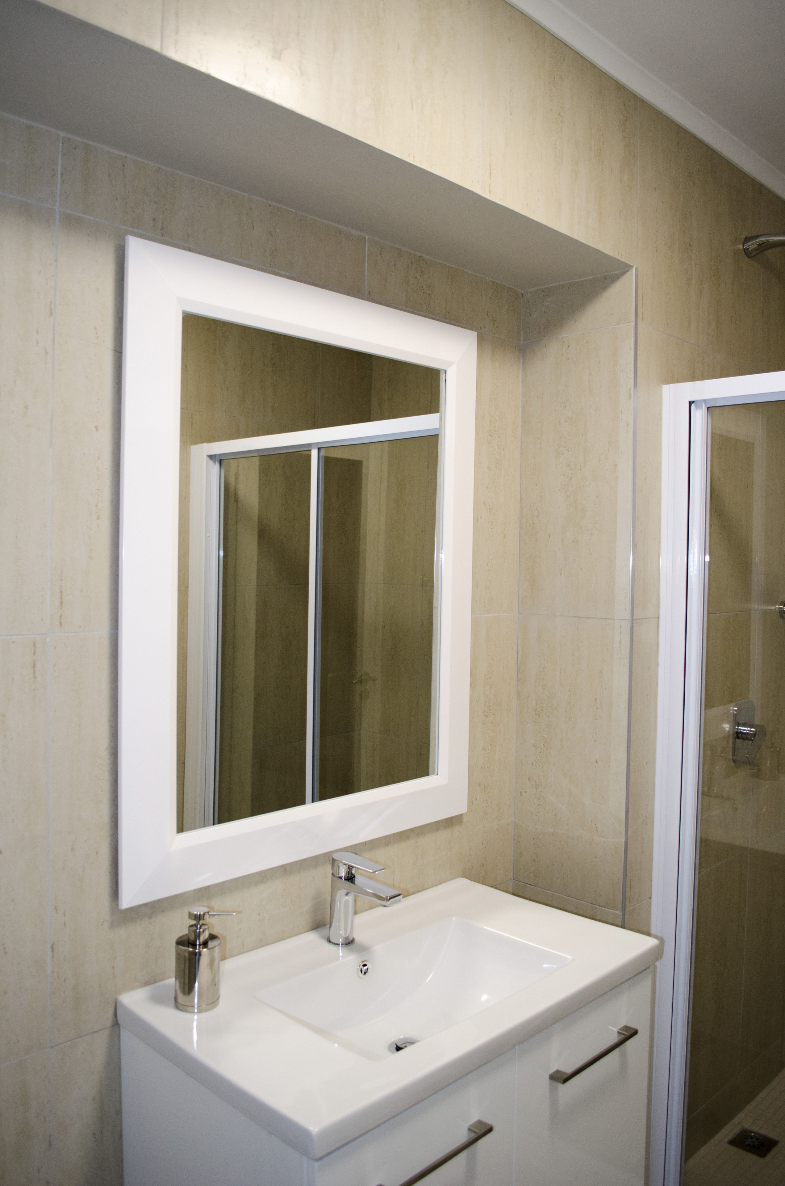 A bathroom with a white sink, a mirror, and a shower.